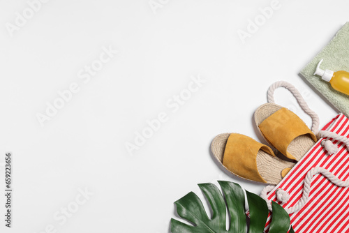 Flat lay composition with bag  green leaf and other beach accessories on white background. Space for text
