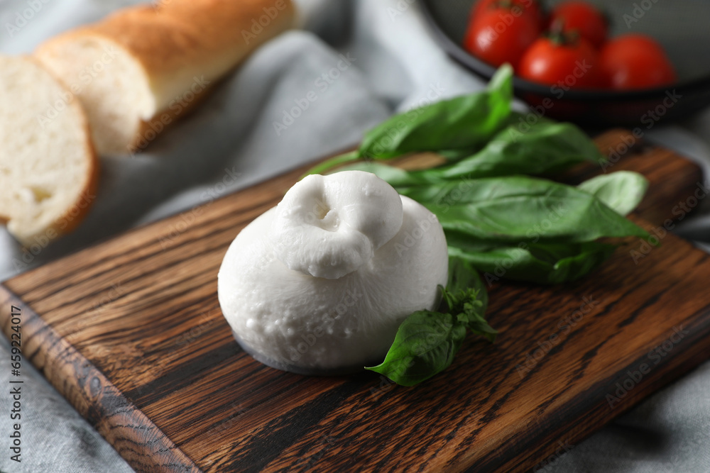 Delicious burrata cheese with basil on light grey tablecloth, closeup Delicious burrata cheese with basil on light grey tablecloth, closeup