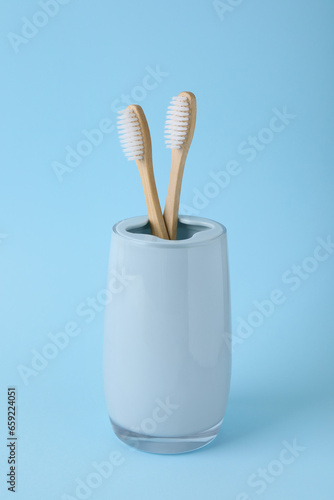 Bamboo toothbrushes in holder on light blue background