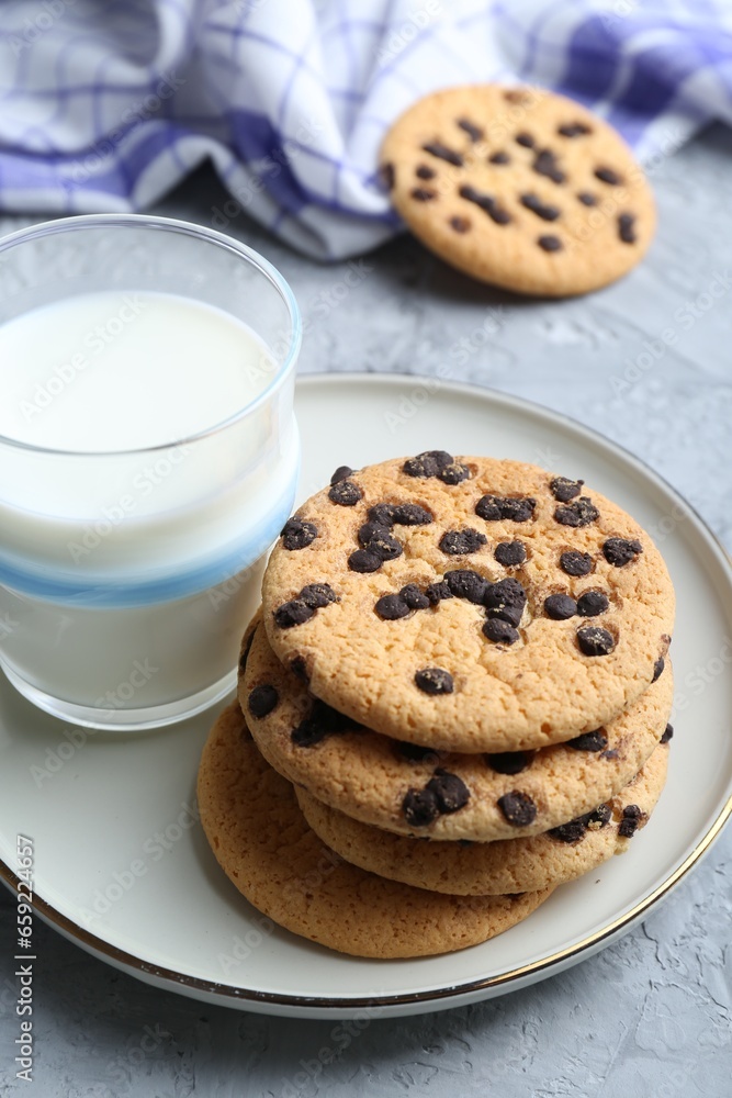 Delicious chocolate chip cookies and glass of milk on grey textured table Delicious chocolate chip cookies and glass of milk on grey textured table