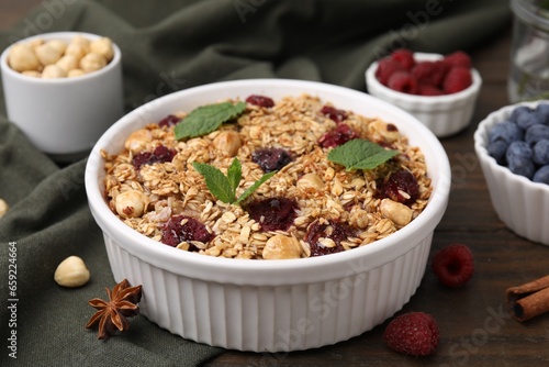 Tasty baked oatmeal with berries and nuts on wooden table, closeup