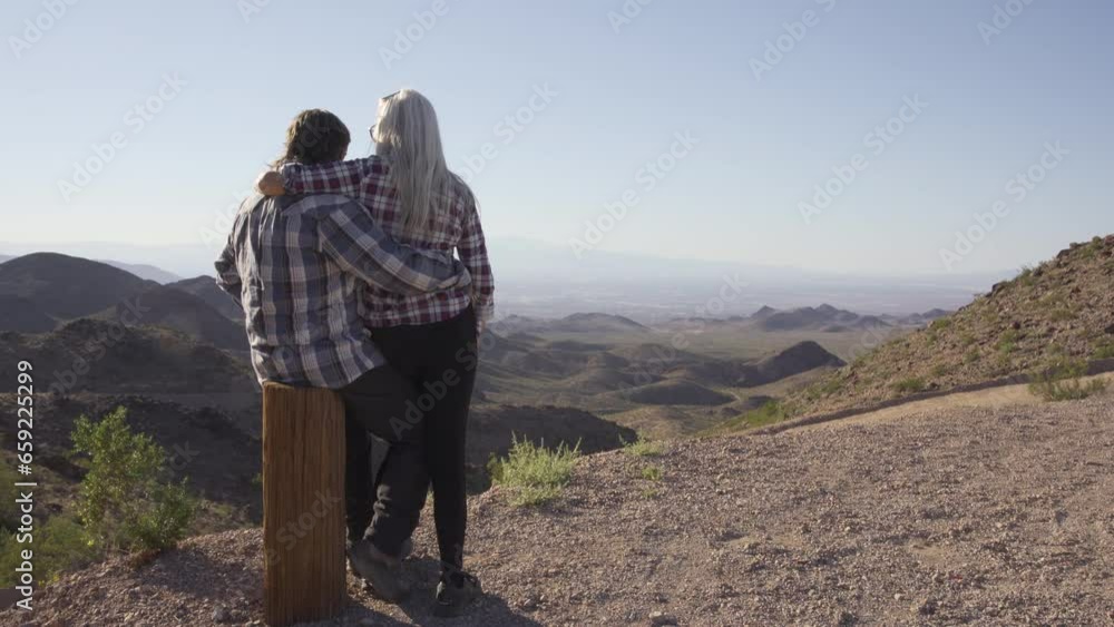 An elderly couple climbed a mountain and watched a magnificent sunset. They hug each other and enjoy of moment An elderly couple climbed a mountain and watched a magnificent sunset. They hug each other and enjoy of moment