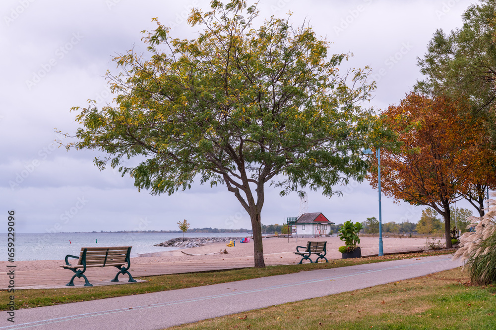 the empty wooden boardwalk and paved bike path along kew beach in toronto's beaches neighbourhood on a fall afternoon park benches lake ontario in background the empty wooden boardwalk and paved bike path along kew beach in toronto's beaches neighbourhood on a fall afternoon park benches lake ontario in background