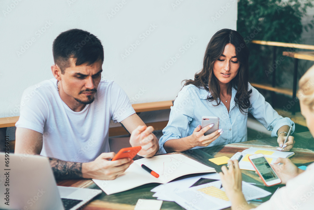 Busy coworkers using gadgets for work in workplace