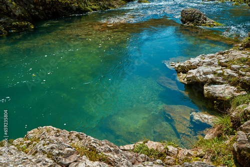The natural pool of the mountain river with emerald clear water