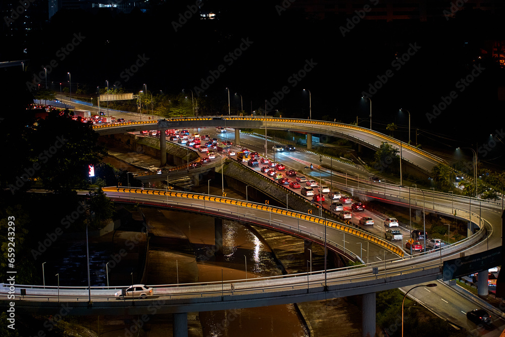 Night photo of a glowing multi-level road junction with heavy traffic. Roads in the metropolis