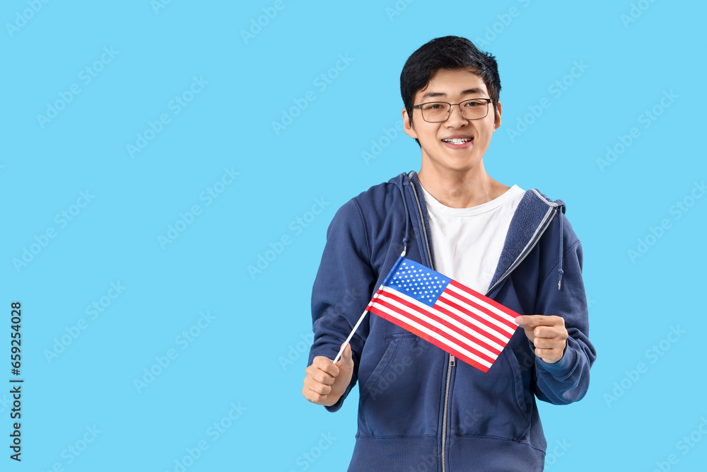 Young Asian man with USA flag on blue background Young Asian man with USA flag on blue background