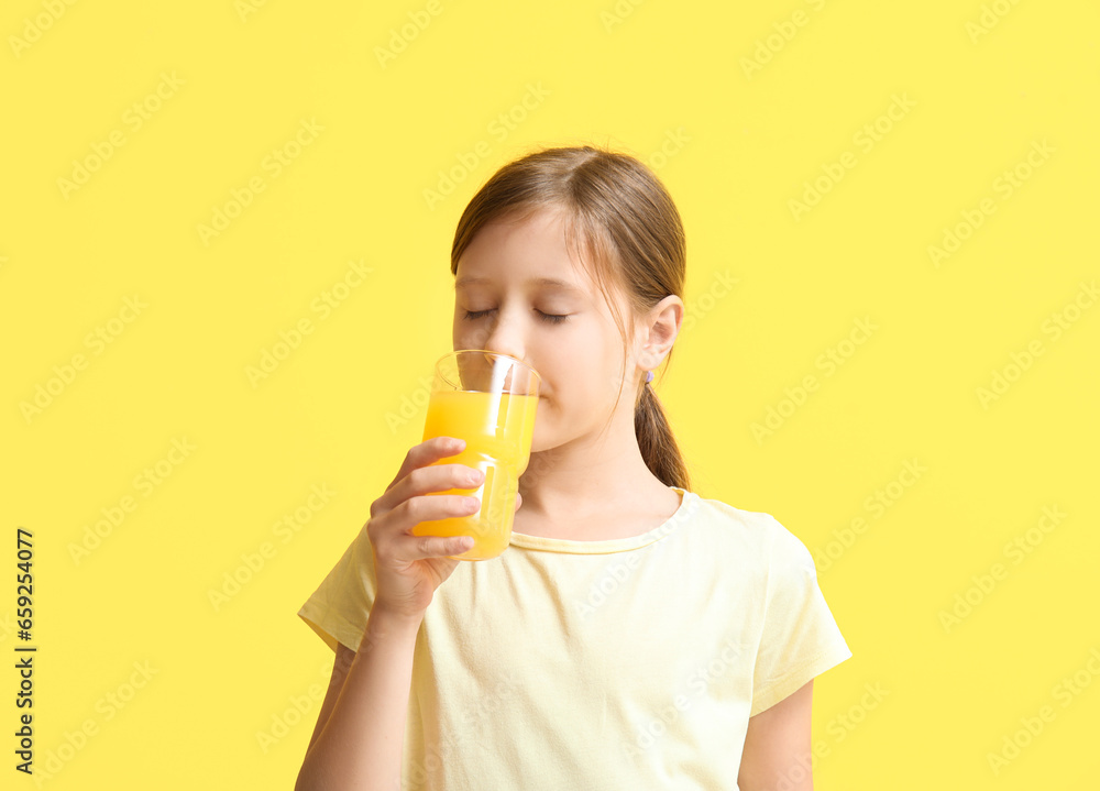 Little girl drinking orange juice on yellow background Little girl drinking orange juice on yellow background