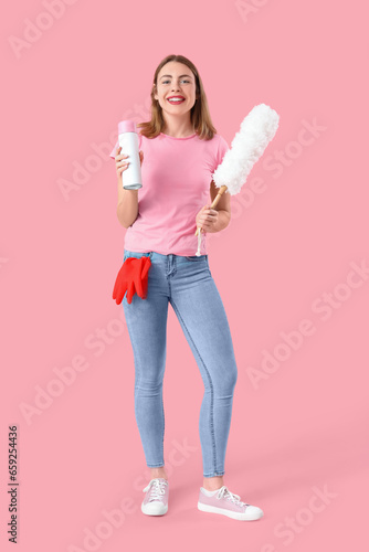 Young woman with air freshener and pp-duster on pink background