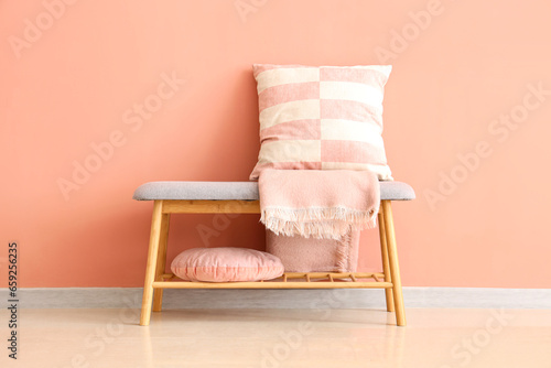 Grey bench with cushions and blanket near pink wall photo