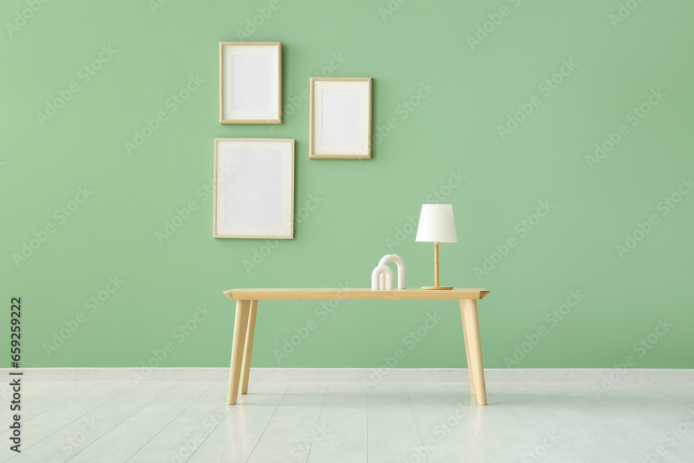Wooden coffee table with lamp and decor near green wall Wooden coffee table with lamp and decor near green wall
