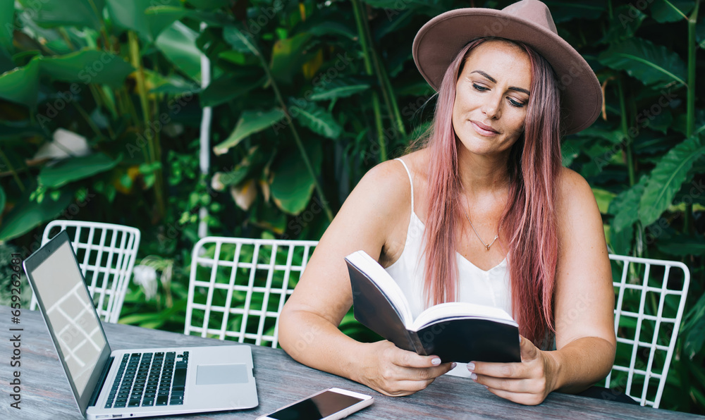 Fototapeta premium Focused woman reading book in park
