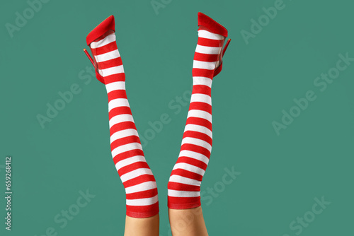 Young woman in Christmas stockings on green background