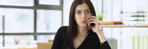 Concerned woman talks with manager on mobile phone in office