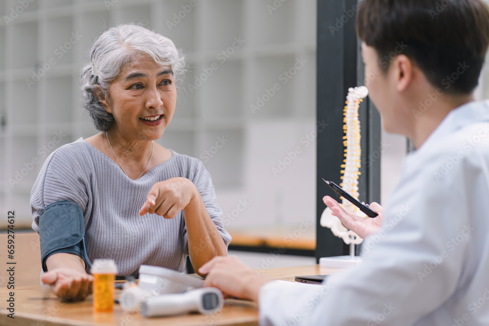 A young doctor using digital tonometer check blood pressure for senior woman. A doctor is holding a senior woman's hand. A young doctor using digital tonometer check blood pressure for senior woman. A doctor is holding a senior woman's hand.