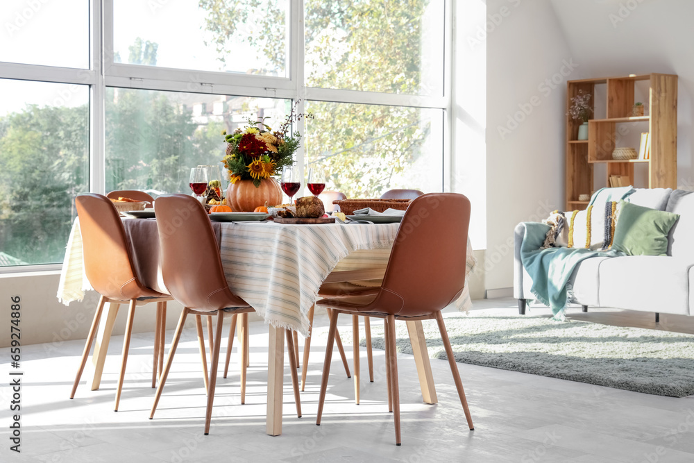 Fototapeta premium Pumpkin with autumn bouquet on festive dining table in room