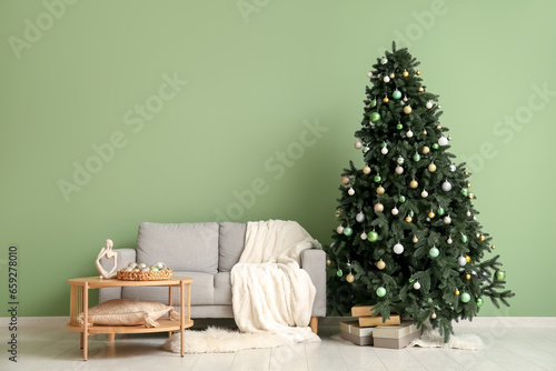 Interior of festive living room with Christmas tree, grey sofa and coffee table