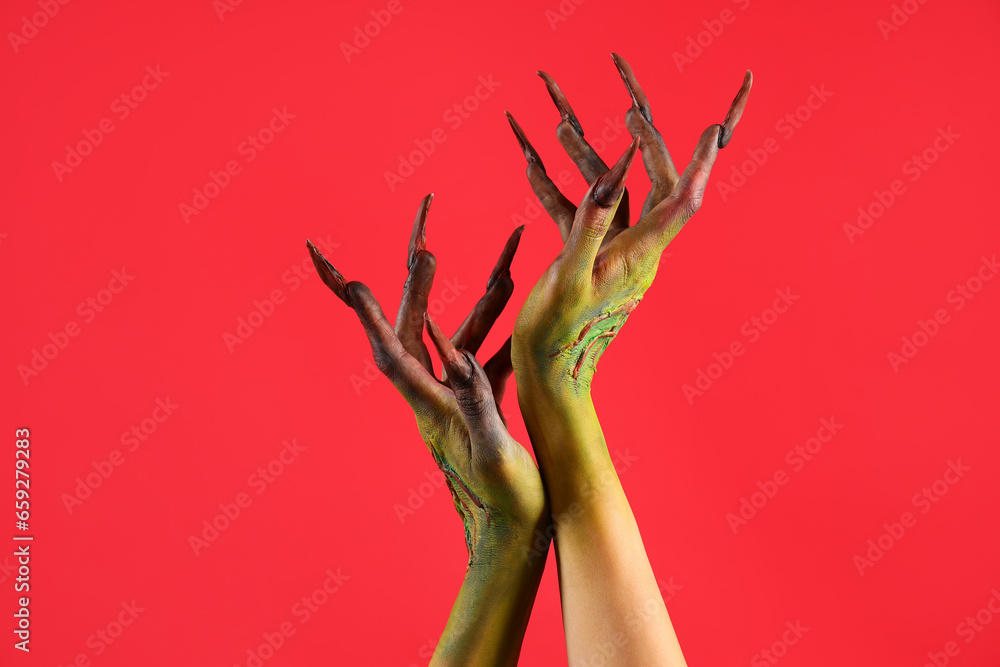 Obraz premium Hands of witch with claws on red background. Halloween celebration
