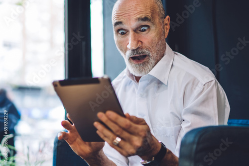 Tablou pe pânză Elderly amazed man browsing tablet