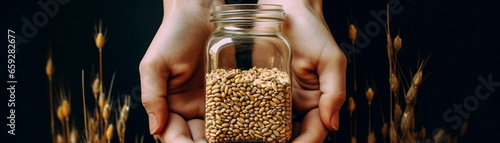 Closeup of hand holding a square glass jar, next to cereal grains background.