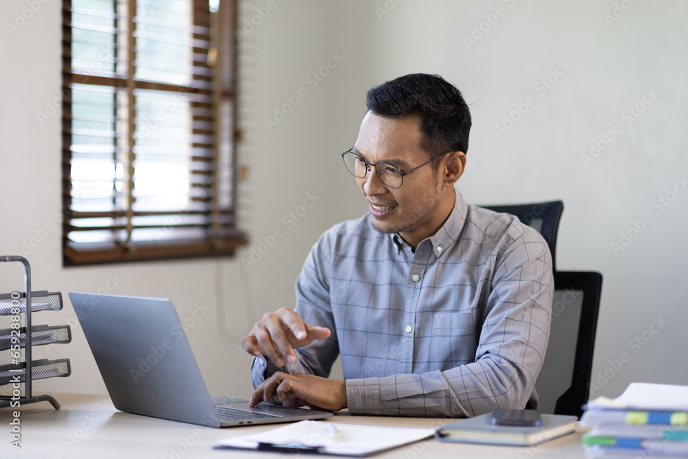 Portrait of Stylish Asian Businessman Works on Laptop, Does Data Analysis and Creative Designer, Looks at Camera and Smiles. Digital Entrepreneur Works on e-Commerce Startup Project Portrait of Stylish Asian Businessman Works on Laptop, Does Data Analysis and Creative Designer, Looks at Camera and Smiles. Digital Entrepreneur Works on e-Commerce Startup Project