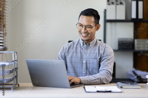 Portrait of Stylish Asian Businessman Works on Laptop, Does Data Analysis and Creative Designer, Looks at Camera and Smiles. Digital Entrepreneur Works on e-Commerce Startup Project