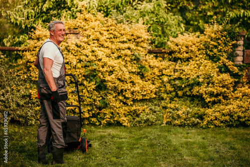 Experienced senior gardener keeps his lawn immaculate while wearing a classic suit © La Famiglia