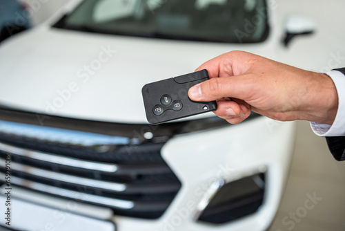 closeup of salesperson holding key against new modern car at showroom © RomanR