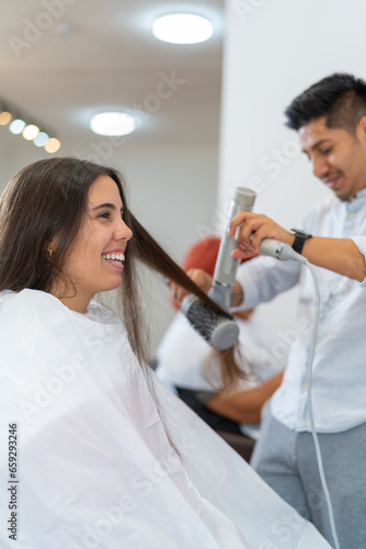 Hairdresser straightening a client s hair in a salon