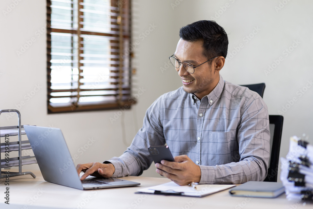 Portrait of a cheerful man using smart phone at home office. freelance asian man entrepreneur and working from home research, planning and info Portrait of a cheerful man using smart phone at home office. freelance asian man entrepreneur and working from home research, planning and info