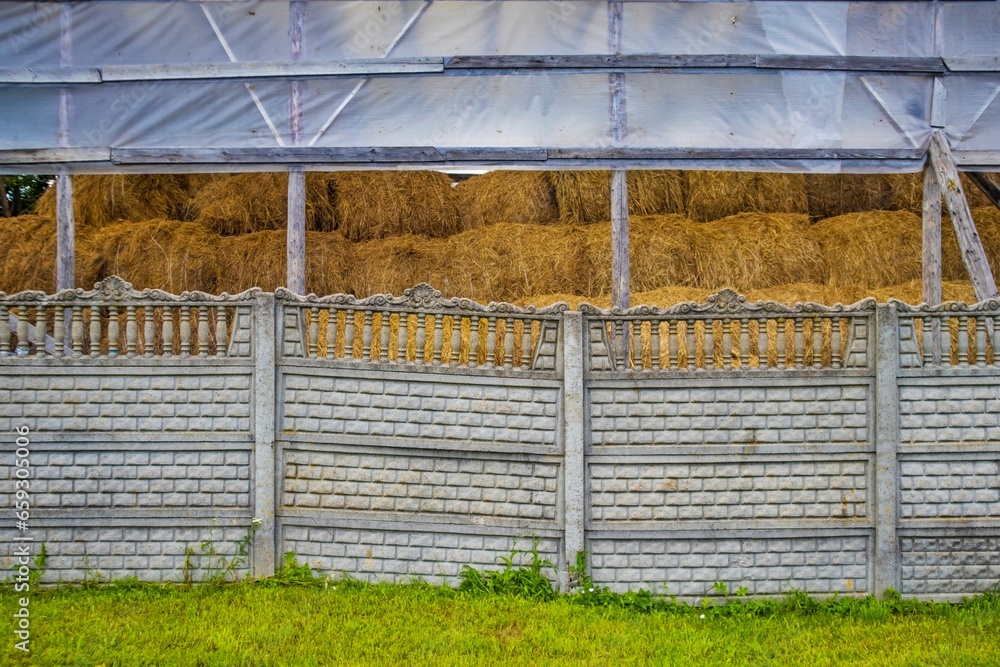Haystacks behind a stone fence under a canopy