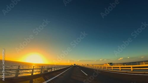 夕暮れの海の上の高速道路を走る自動車