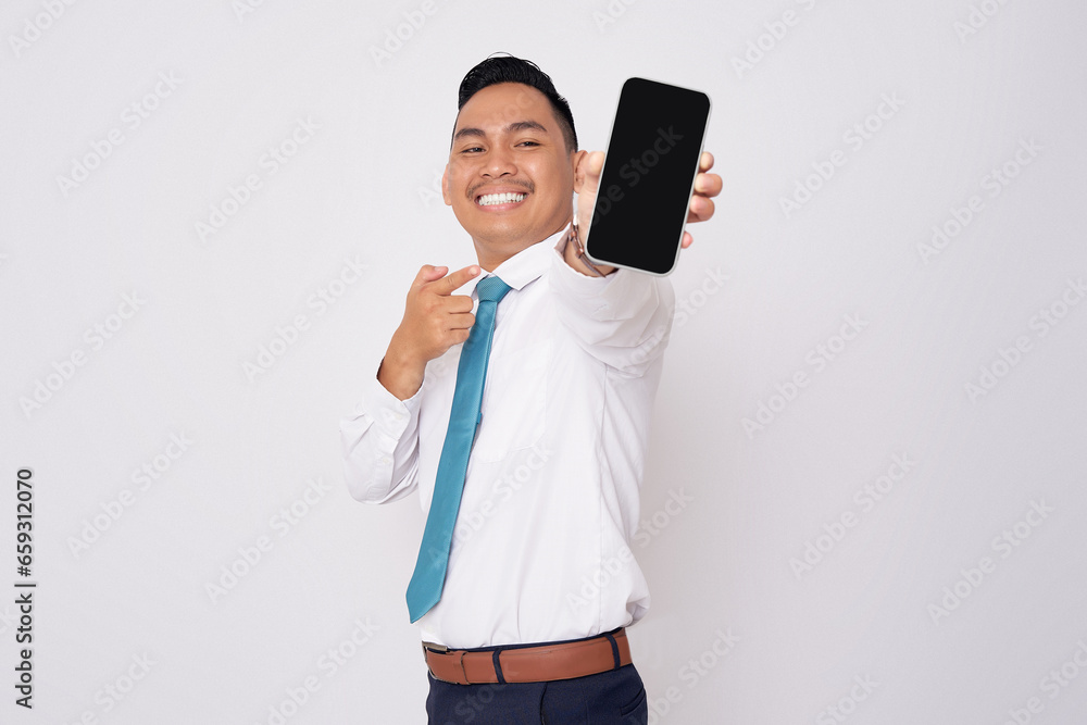 Smiling happy young Asian man in formal wear pointing finger at mobile phone with blank screen, recommend the app for advertisiment isolated on white background Smiling happy young Asian man in formal wear pointing finger at mobile phone with blank screen, recommend the app for advertisiment isolated on white background