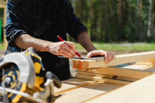Engineer measuring wood at construction site on sunny day photo