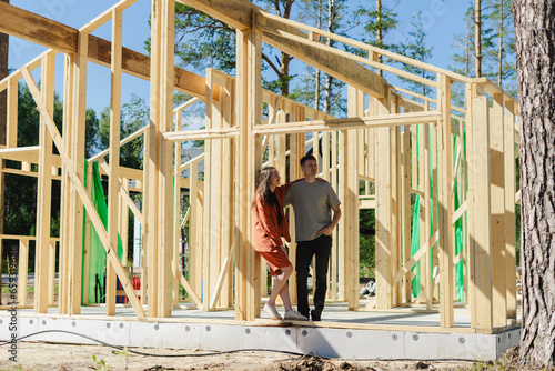Couple standing at wooden construction frame on sunny day