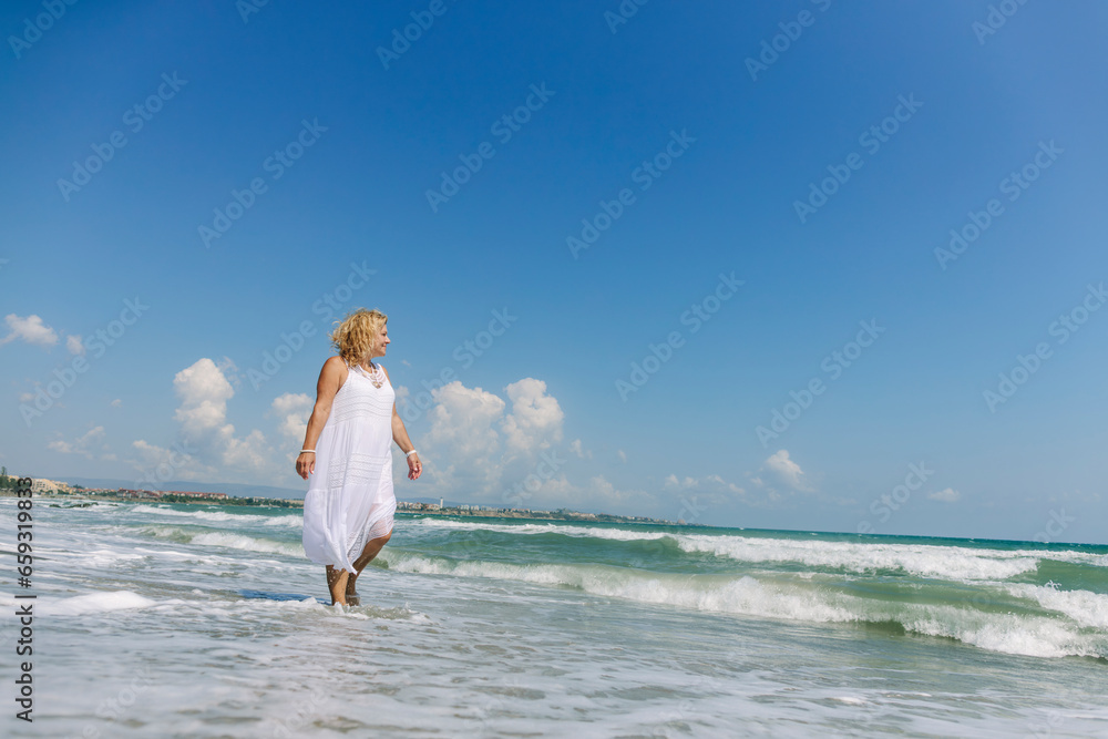 Senior woman walking on shore at beach Senior woman walking on shore at beach