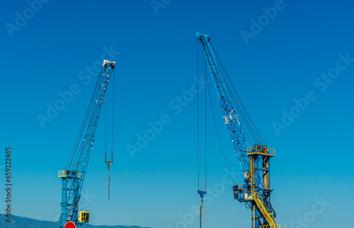 Wallpaper Mural Two construction tower cranes at a construction site against a blue sky with clouds. Torontodigital.ca