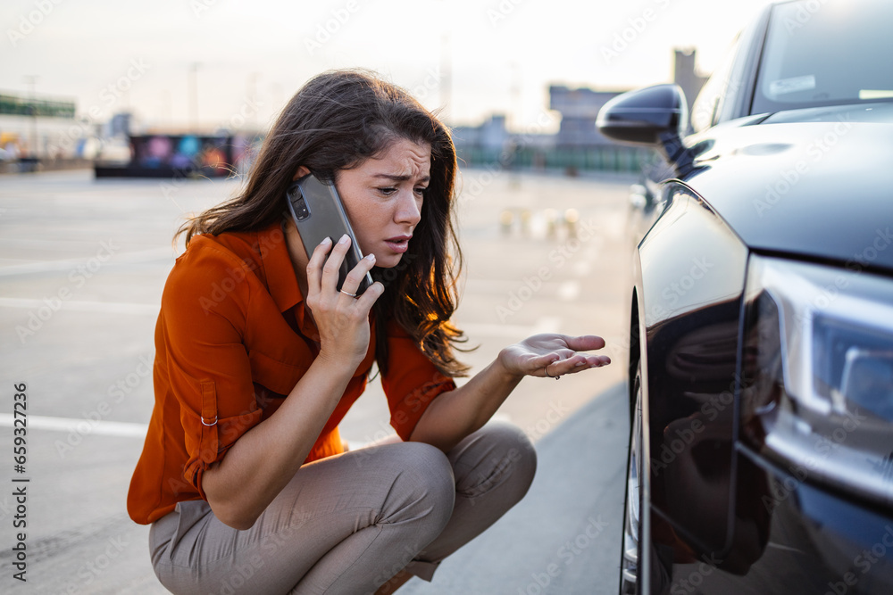 Naklejka premium Woman calling for assistance with flat tire on car in the city. Young woman with high heels in the city with flat tire, frustrated near broken car