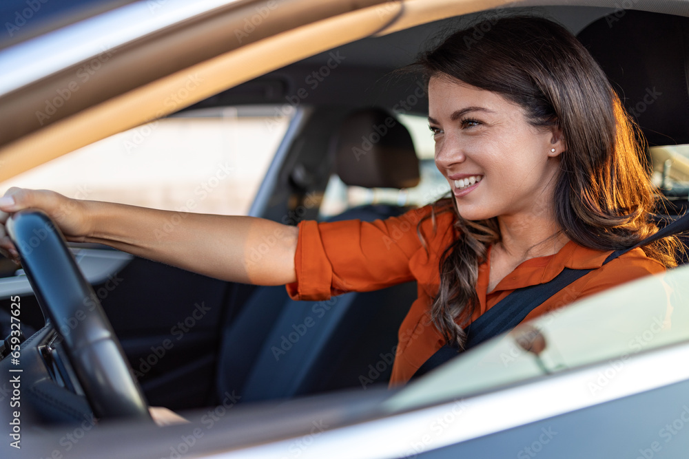 Happy business woman traveling with her car around the city. Beautiful young happy smiling woman driving her new car at sunset.