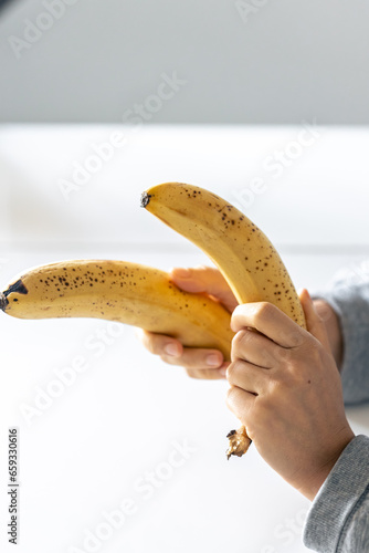 Ripe yellow bananas in female hands on a blurred background.