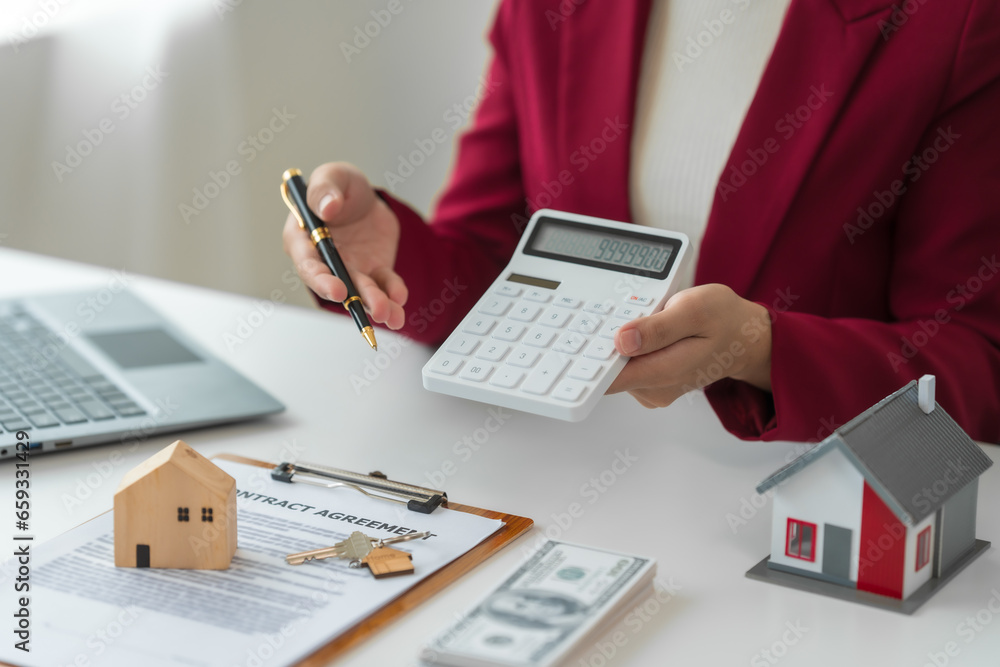 Fototapeta premium A young Asian real estate agent is reviewing documents and calculating interest rates to inform tenants of monthly installments before entering into contracts to buy or sell real estate.