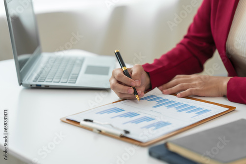 A young Asian real estate agent is reviewing documents and calculating interest rates to inform tenants of monthly installments before entering into contracts to buy or sell real estate.