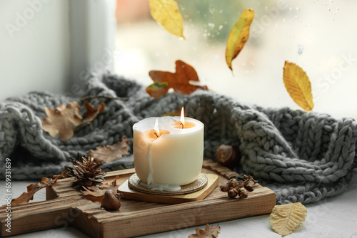 Autumn still life with a burning candle  leaves and a knitted element.