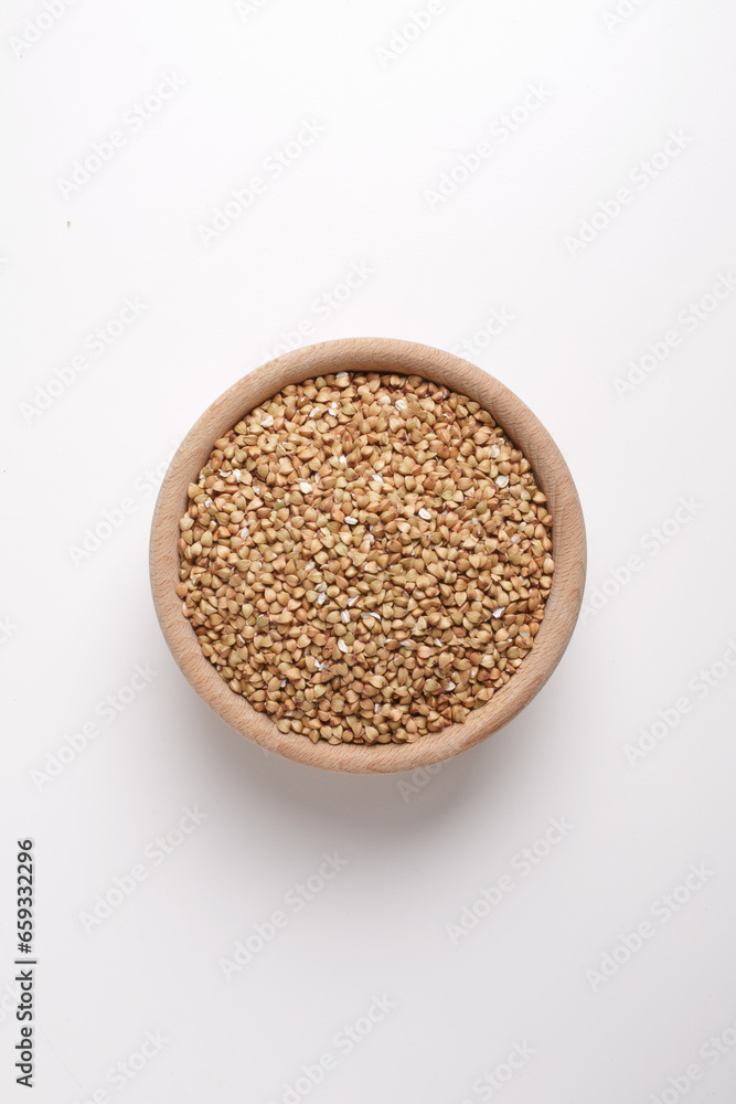 buckwheat in wooden bowl on white background shot from above