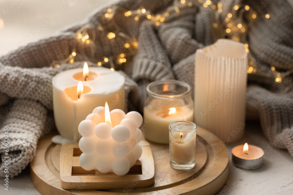 A cozy composition with candles, a knitted element and a garland. A cozy composition with candles, a knitted element and a garland.