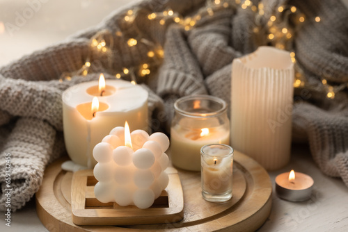 A cozy composition with candles  a knitted element and a garland.