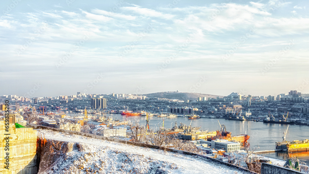 Panoramic view of the city and the bay in cold warm colors, winter landscape of the Golden Horn Bay Vladivostok 11.22.2020, Water and ships reflect the sunset. 