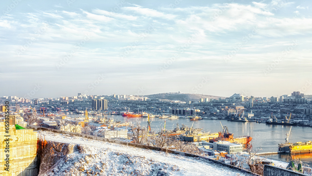 Fototapeta premium Panoramic view of the city and the bay in cold warm colors, winter landscape of the Golden Horn Bay Vladivostok 11.22.2020, Water and ships reflect the sunset. 