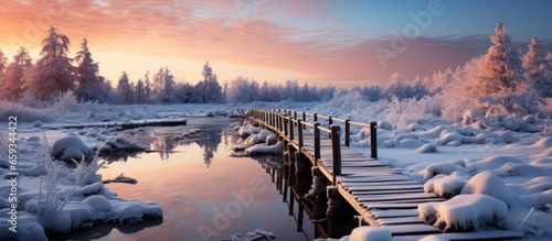 Winter landscape with frozen river and wooden bridge at sunset. Panorama