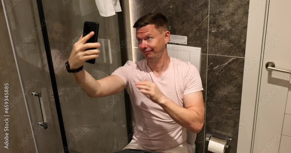 Man sitting on toilet and taking selfie on his mobile phone camera 4k movie. When you are bored at home concept Man sitting on toilet and taking selfie on his mobile phone camera 4k movie. When you are bored at home concept